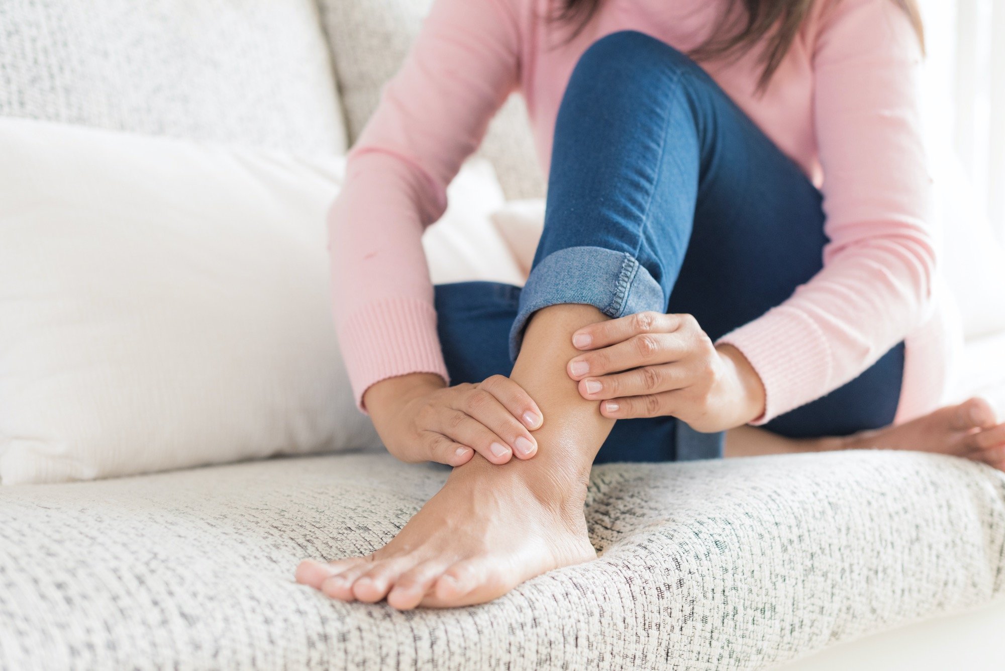 Woman Holding Inflamed Ankle on Couch