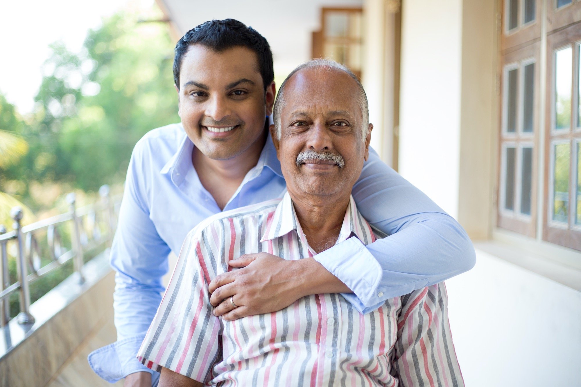 Son and Father Smiling at Camera Before Reviewing Medical Financing