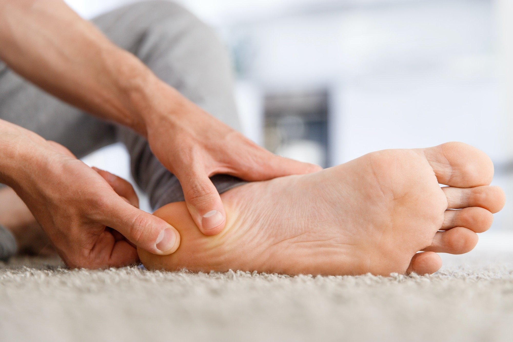 Man Showing Off Heel Pain on Floor