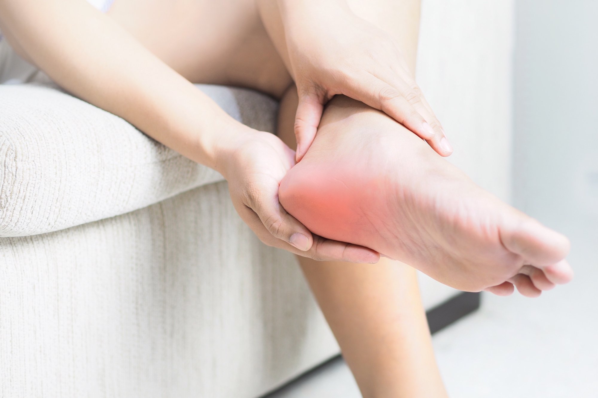 Woman Sitting on Couch Evaluating Aching Heel Pain